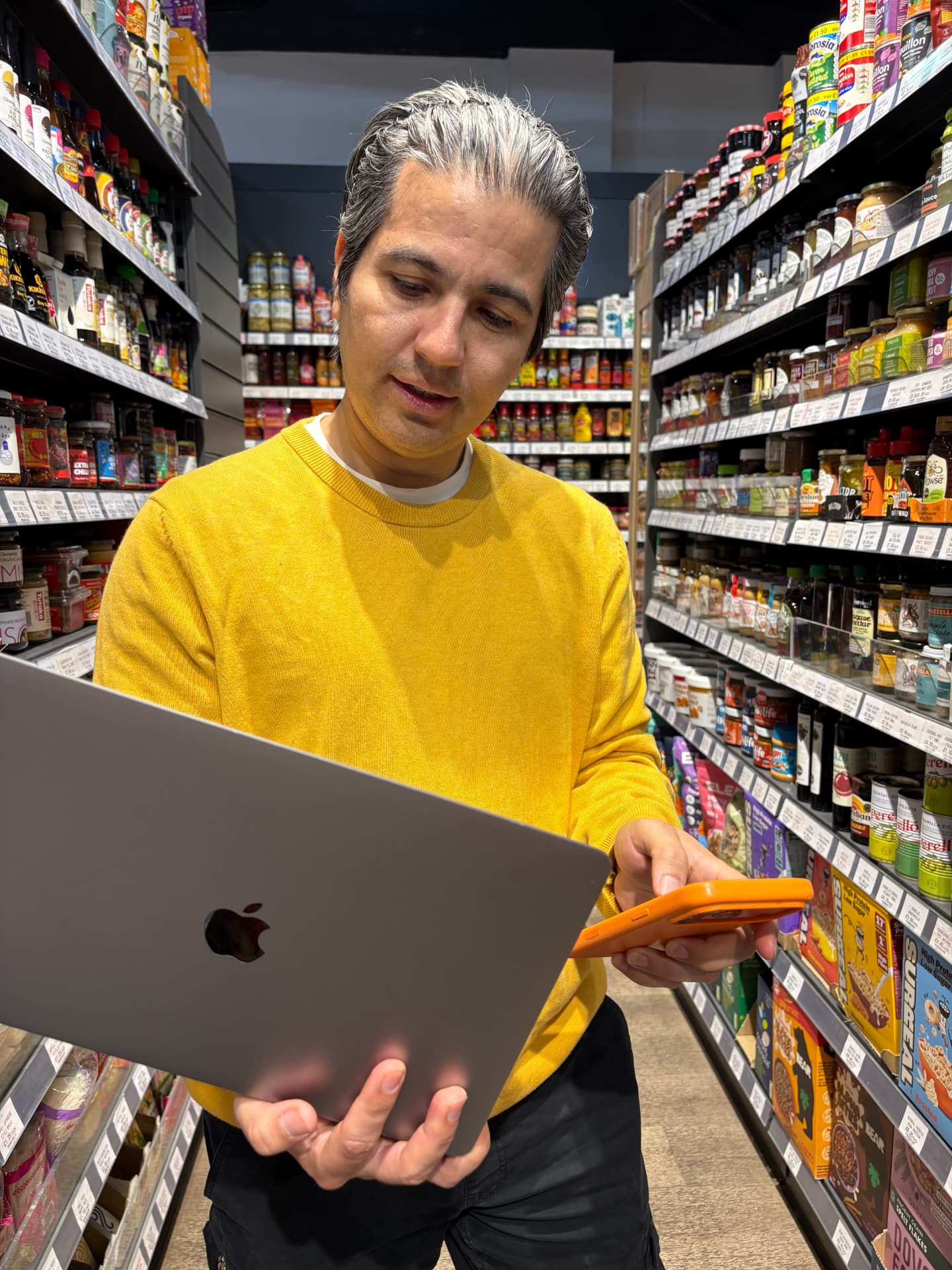 A shopkeeper glancing between multiple order notifications on a counter